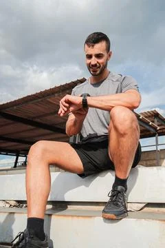 Vertical. Focused man checking his smartwatch while engaged in an active tr.. Stock Photos