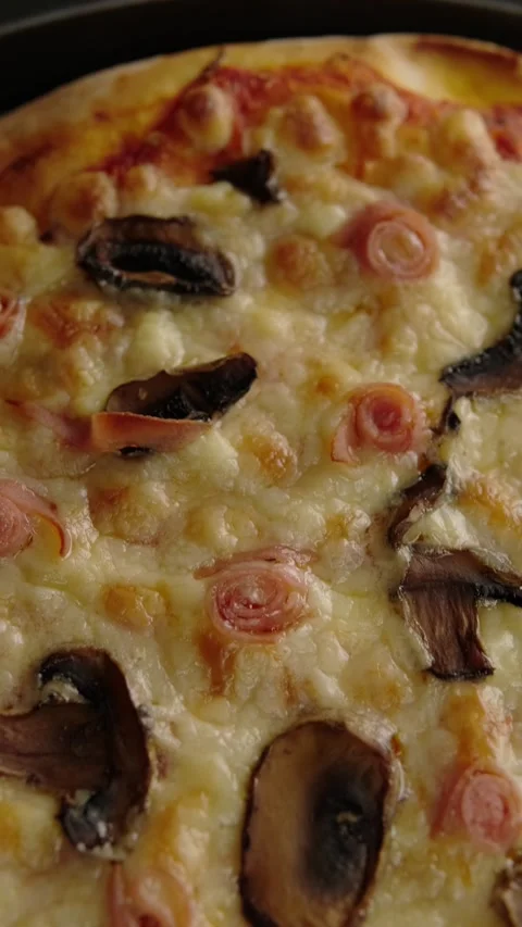 Vertical food video, close up view of a pizza with mushrooms and ham rolls Stock Footage 282564649