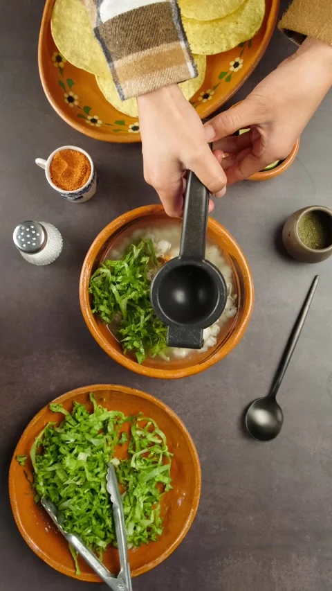 Vertical food video preparing mexican pozole, mexican woman squeezing lemon Stock Footage 280360926