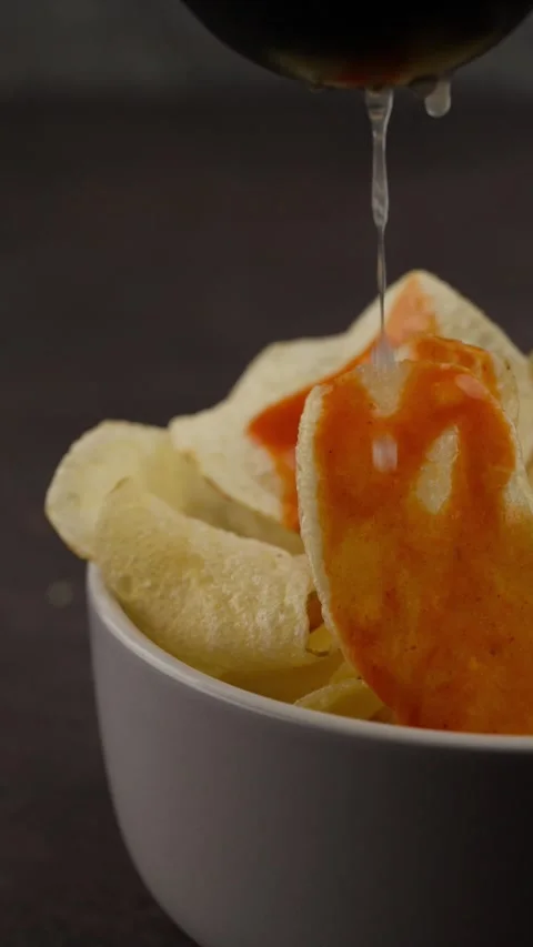 Vertical food video, Squeezing a lemon with a juicer on circular potato chips Stock Footage 280327019