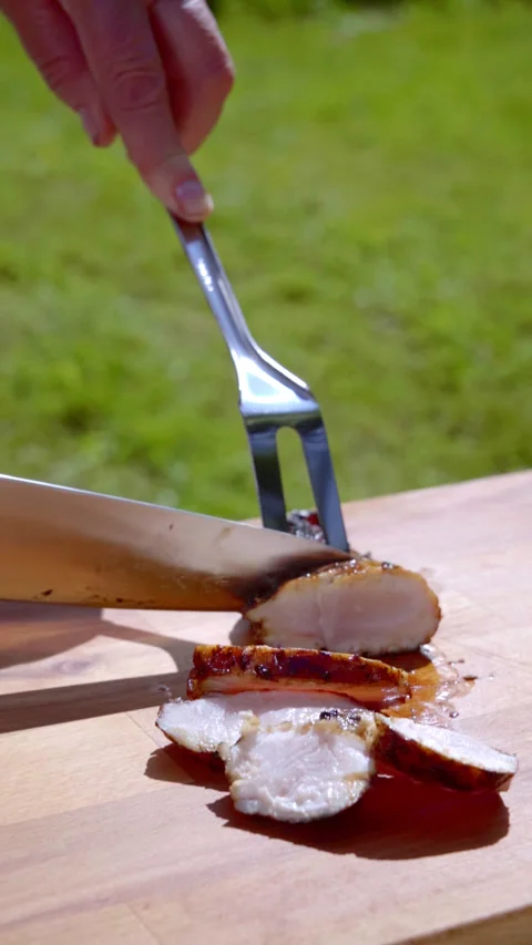 Vertical footage. A chef cuts a grilled chicken on a wooden cutting board. Stock-Footage 317932986