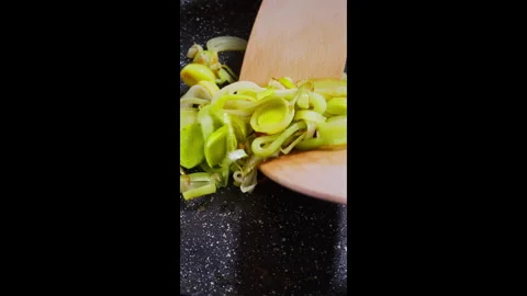 Vertical footage. Chef frying leeks in a pan and stirring them with a spatula. Stock Footage 302637560