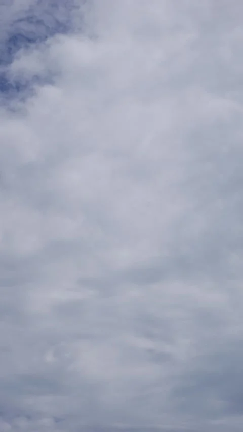 Vertical footage of drifting clouds moving gracefully through a bright sky Stock Footage 320812256