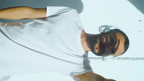 Vertical footage of man wearing wireless headphones outside. trying to look at Stock Footage 168716701