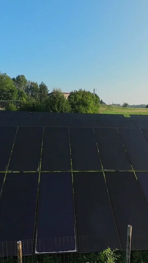 Vertical footage of a solar panel array in a green field under a clear blue sky Video stock 287934858