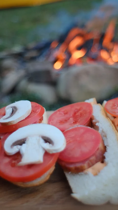 Vertical footage of unknown man cooking sandwich near campfire and tent Stock Footage 271225087
