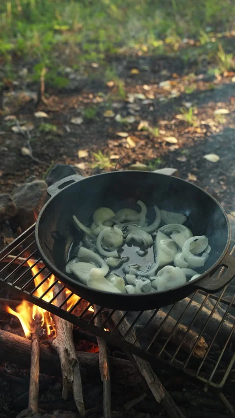 Vertical footage of unknown man fries onions in oil on hot fire in autumn nature Stock Footage 286309768