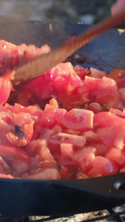 Vertical footage of unknown young man cooking cut tomatoes with red peppers Stock Footage 301365539