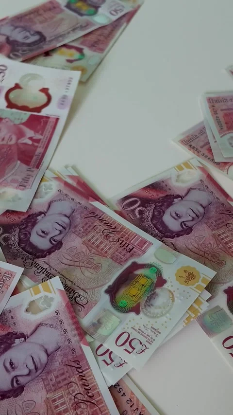 Vertical format British £50 notes falling in ultra slow motion onto a white Stock Footage 334565306
