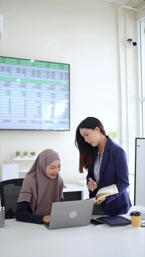 Vertical format of coworkers exchanging ideas beside laptop in bright office Stock Footage 333516741