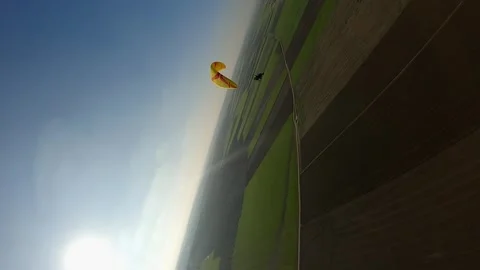 Vertical format: FPV aerial tracks paraglider in sky over agriculture Stock Footage 262306449