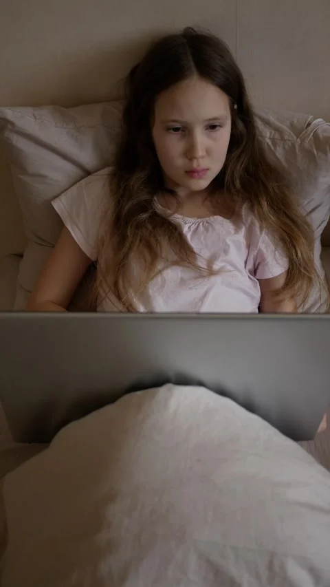 Vertical format. Girl using laptop in bed. A schoolgirl lies on the bed and uses Stock Footage 274186705