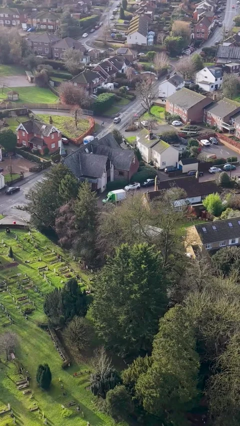 Vertical format left drone pan over Wheathampstead, church cemetery and junction Stock Footage 328748591