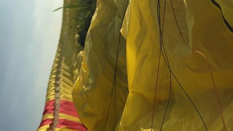 Vertical format: Narrow focus yellow nylon paraglider canopy on ground Stock Footage 262303463