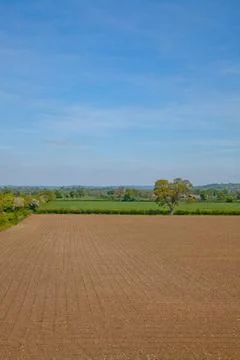 Vertical format picture of idyllic flat countryside with a large ploughed field Stock Photos