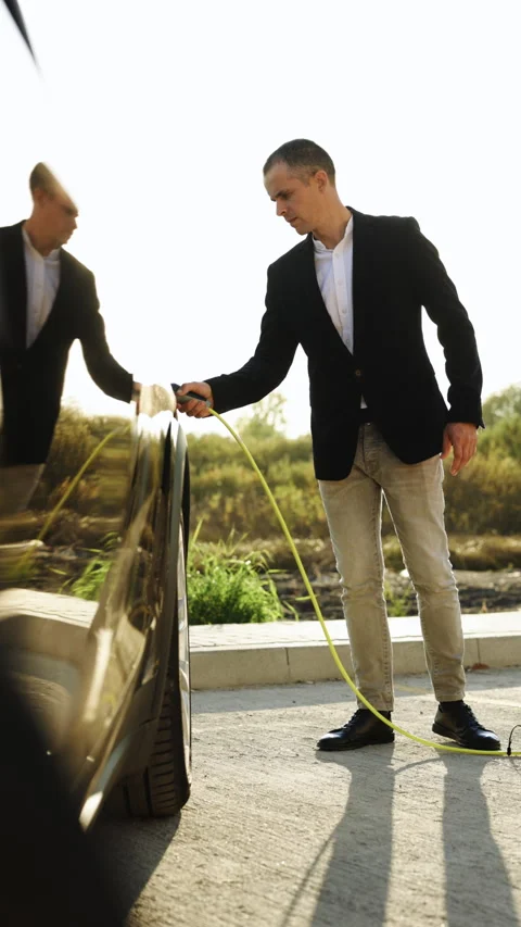 Vertical Format Video of businessman plugging electric car from charging station Stock Footage 305542391