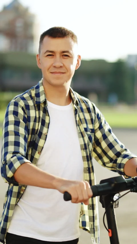 Vertical Format Video of hipster man leaning on electric scooter and looking at Stock Footage 304177518