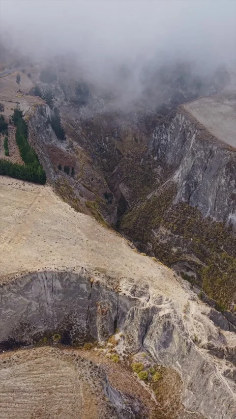 Vertical format video of misty clouds hovering above deeply carved mountain 스톡 동영상 308405305