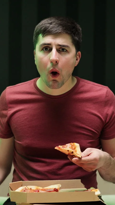 Vertical Format Video of Portrait of young man watching TV eating pizza sitting Stock Footage 303493181