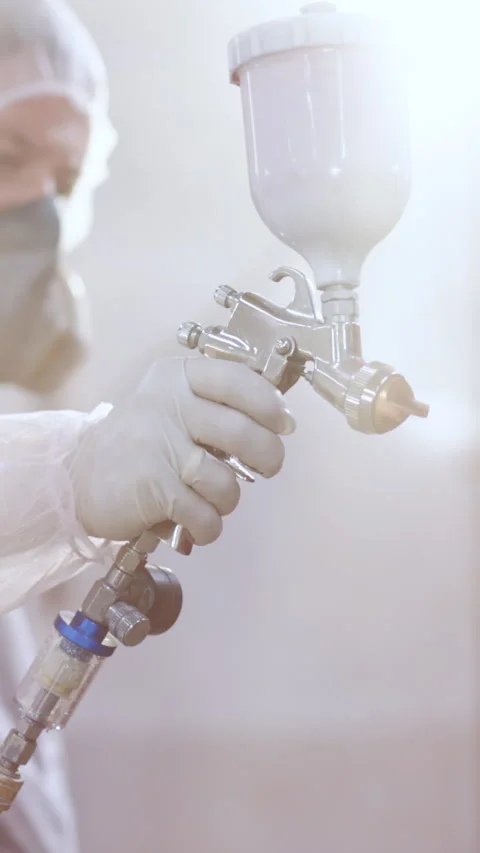 Vertical Format Video of Professional car painter is painting a body work. Male Stock Footage 303843498