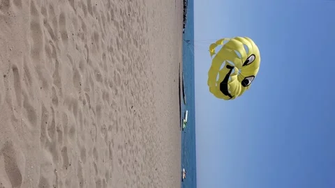 Vertical format video of summer beach with yellow parasailing wing flying in Video stock 156070260