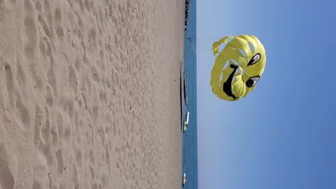Vertical format video of summer beach with yellow parasailing wing flying in Stock Footage 156172500
