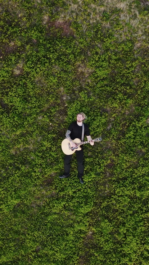Vertical Format Video of Top View a rock man lying on the ground and playing an Stock Footage 304816122