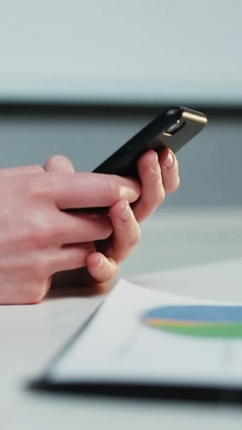 Vertical Format Video of woman's hands with a phone in the background of a Stock Footage 303008609