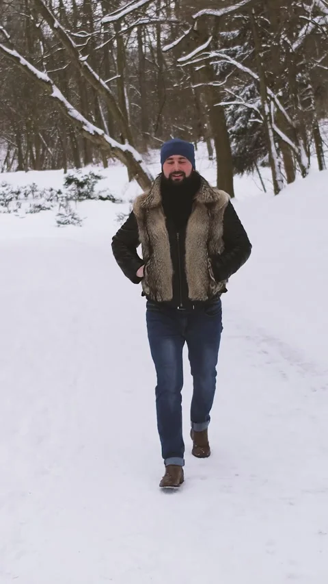 Vertical Format Video of young bearded man in winter clothes walks through a Stock Footage 309653192