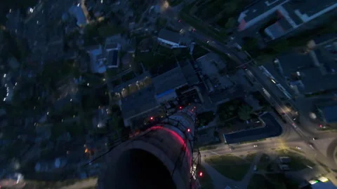 Vertical FPV Dive Along Industrial Chimney Over Lit City Grid at Dusk Video stock 310302801