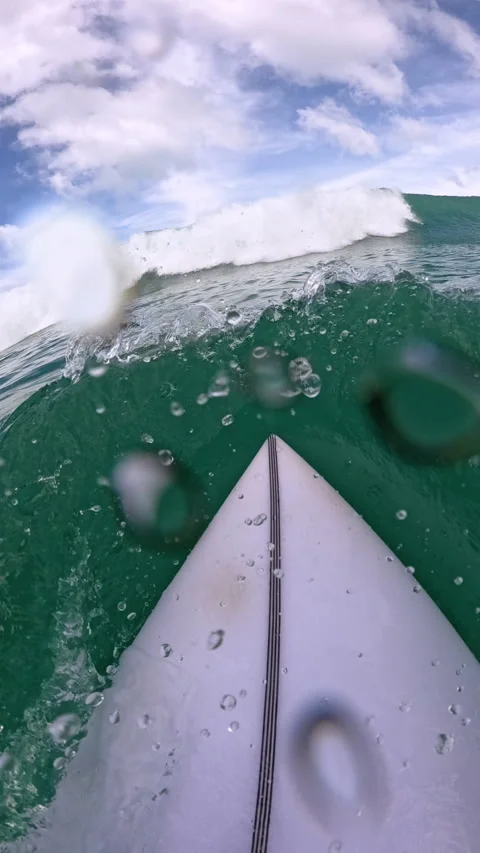 VERTICAL, FPV, SLOW MOTION: Surfer makes duck dive in front of approaching wave Stock Footage 339087190