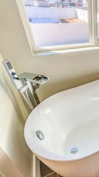 Vertical frame Bathroom interior with a gleaming bathtub against white wall and Stock Photos