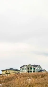 Vertical frame Bright cloudy sky over multi storey home on mountain covered with Stock Photos