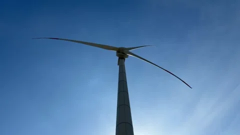 Vertical frame captures a wind turbine with blades in motion, rotating against 库存影片 329304413