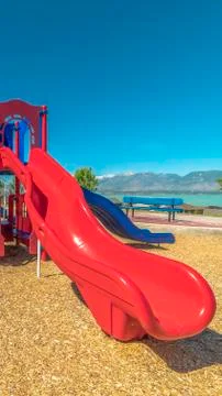 Vertical frame Focus on slides at a park with view of lake and distant Stock Photos