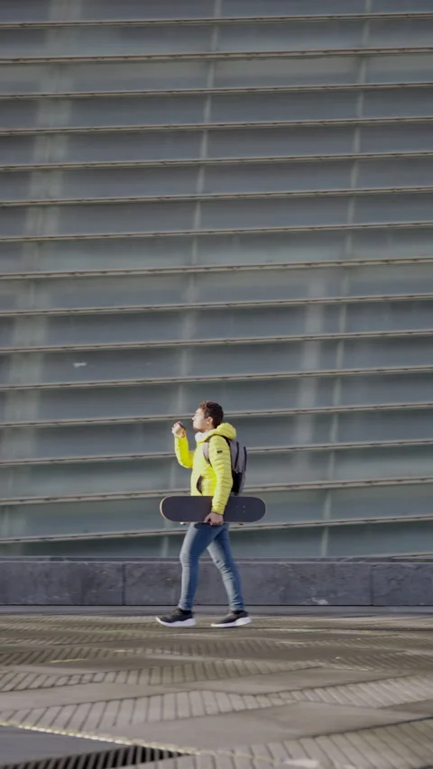 Vertical frame of hispanic cool man walking while holding skateboard Vidéo 222566406