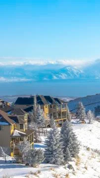 Vertical frame Homes on pristine snowy terrain overlooking valley lake and Stock Photos