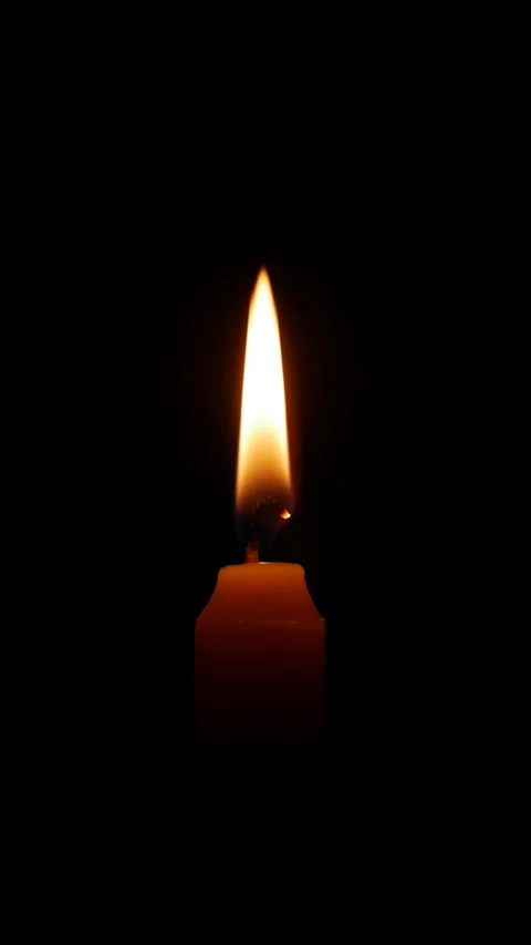 A vertical frame shows a single candle flame glowing against deep blackness as Stock Footage 322058379