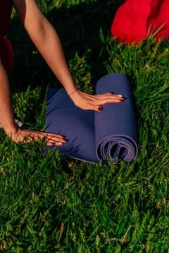 Vertical frame womens hands spread out a sports mat on green grass in the par 스톡 사진
