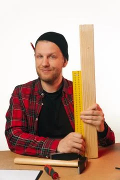 Vertical frame , young Caucasian guy a carpenter with a beard works in a carp Stock Photos