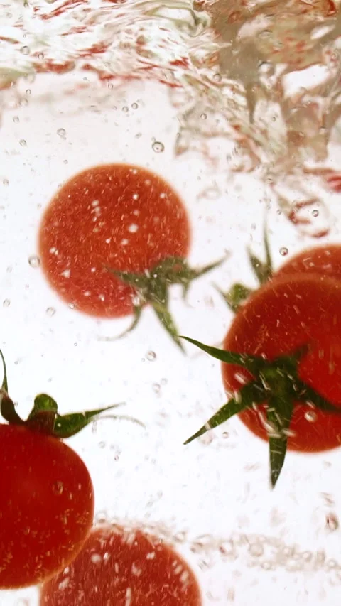 Vertical fresh red cherry tomatoes moving and splashing in water in slow motion Stock Footage 312590990