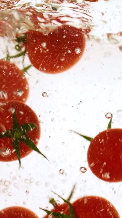 Vertical fresh red cherry tomatoes moving and splashing in water in slow motion Stock Footage 313027542