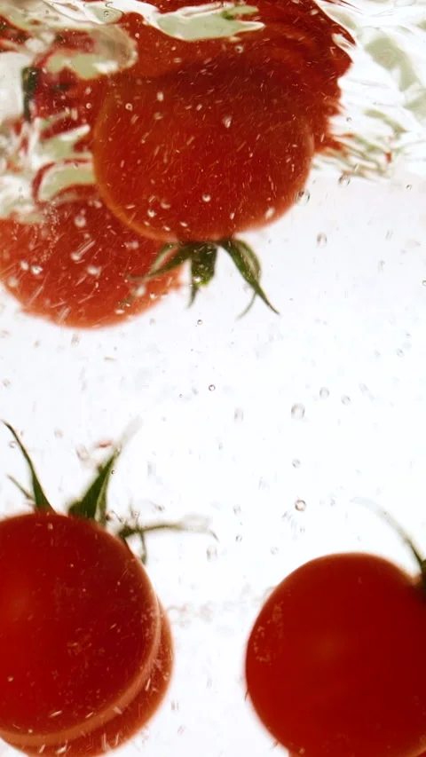 Vertical fresh red cherry tomatoes moving and splashing in water in slow motion Stock Footage 316037186
