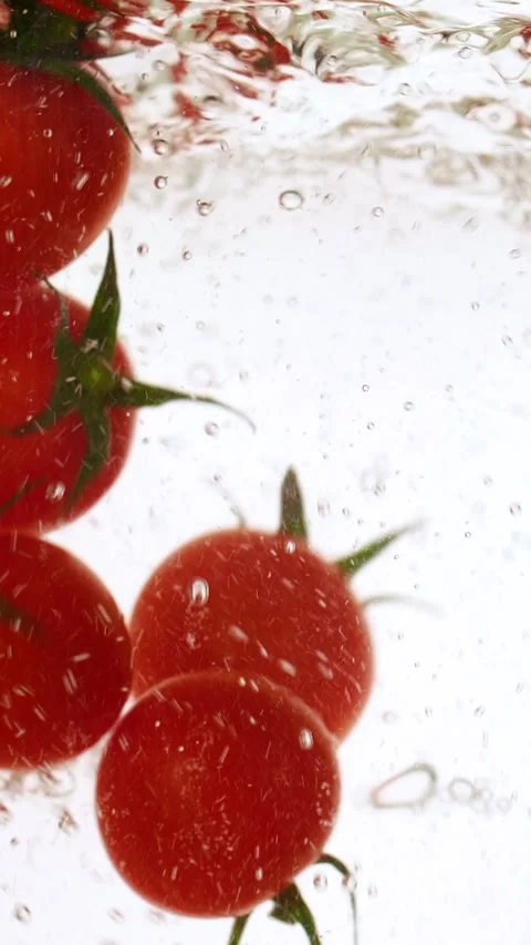 Vertical fresh red cherry tomatoes moving and splashing in water in slow motion Stock Footage 316576918