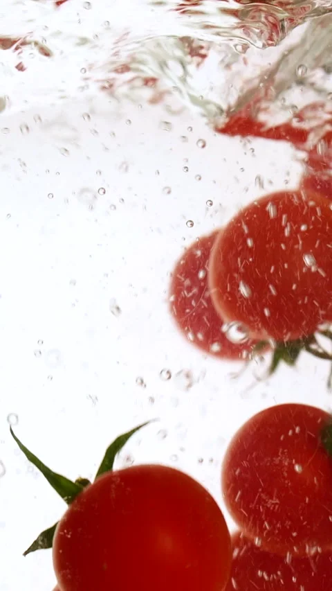 Vertical fresh red cherry tomatoes moving and splashing in water in slow motion Stock Footage 317529738