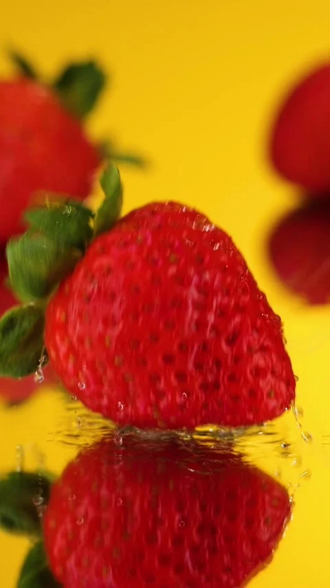 Vertical Fresh Red Strawberry Falling Into Water Splash on Yellow Slow Mo Stock Footage 292560314
