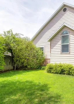 Vertical Front yard of a house with trees, plants and green lawn Stock Photos