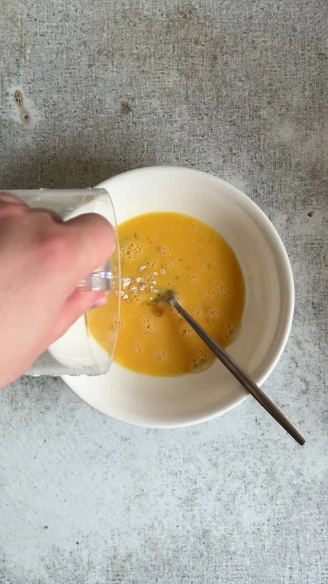 Vertical Full HD video. Man pours oatmeal from cup into bowl with yolks Stock Footage 278119257