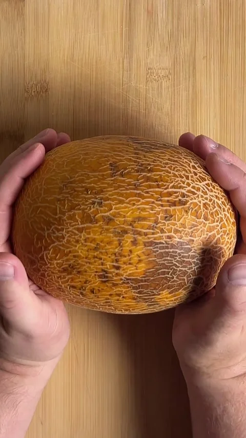 Vertical Full HD video. Man puts yellow melon on wooden cutting board Stock Footage 286176926