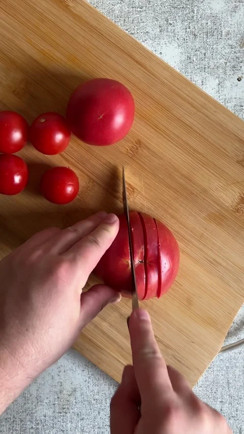 Vertical Full HD video. Top view. Man cuts red fresh juicy small tomatoes Stock Footage 277755996